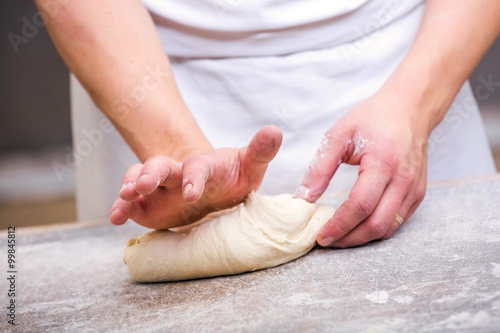 Close-up the hand of a baker kneading and shaping dough