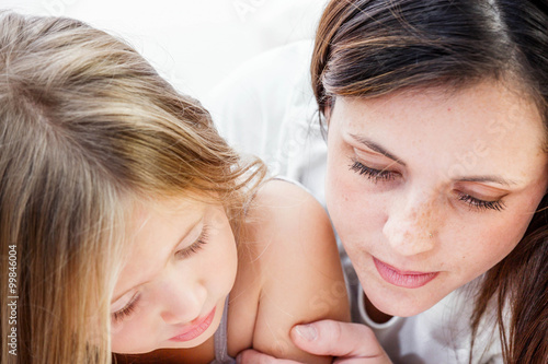 Closeup of a smiling young woman playing with her child on white background