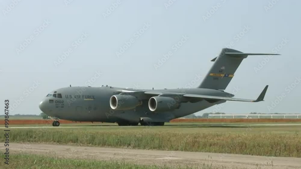Wide view of Boeing C-17 Globemaster military transport taxiing at airfield. Used by the United States Air Force and developed by McDonnell Douglas. Control tower in background. Wide view of Boeing C-17 Globemaster military transport taxiing at airfield. Used by the United States Air Force and developed by McDonnell Douglas. Control tower in background.