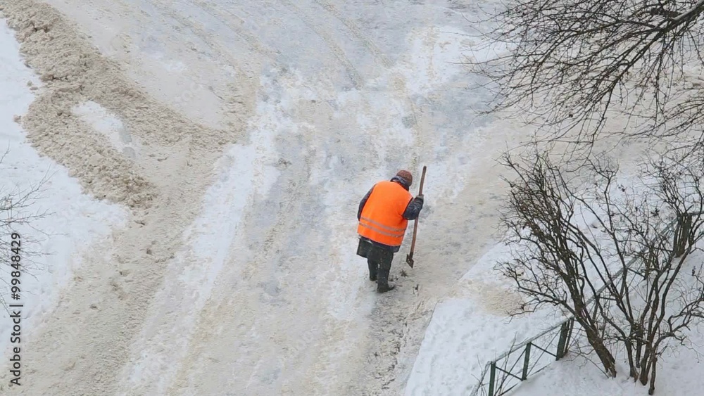 Anonymous female worker cleaning dangerous pavement from ice. Woman shoveling snow. Anonymous female worker cleaning dangerous pavement from ice. Woman shoveling snow.