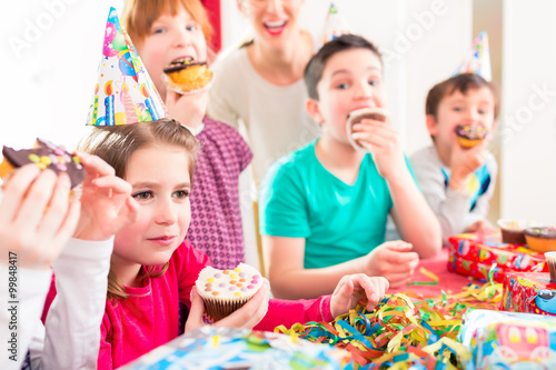 Children at birthday party with muffins and cake