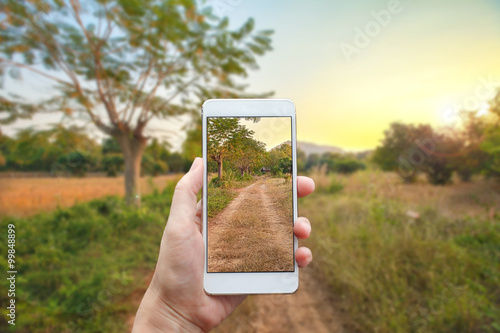 Business conceptual- Focused on left hand holding mobile with urban road blurred background
