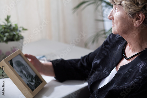 Senior widow reminiscing her husband photo