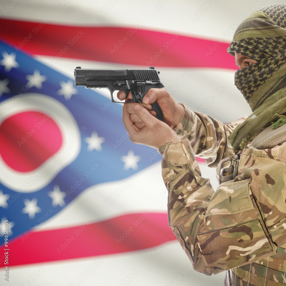 Fototapeta premium Side view of man in camouflage holding gun against Flag of Ohio