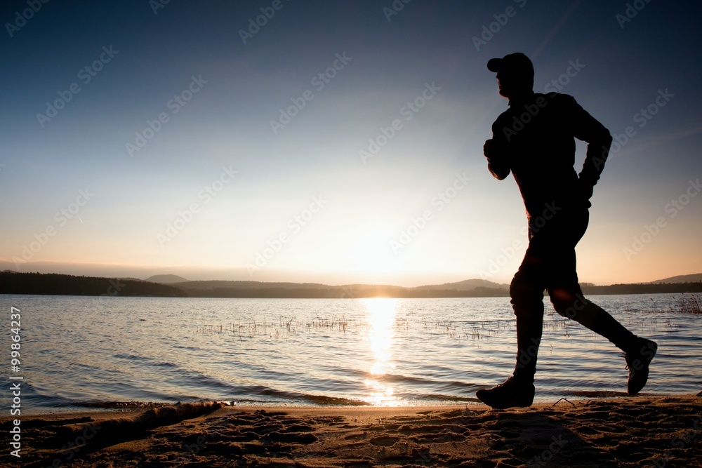 Running man on beach. Sportsman run in baseball cap, jogging guy during the sunrise