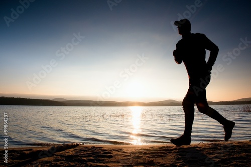 Running man on beach. Sportsman run in baseball cap, jogging guy during the sunrise