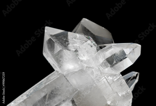 Cluster of several transparent rock crystals close-up, isolated on a black background