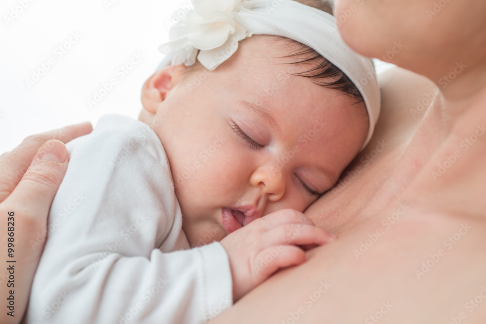 Closeup of a baby girl sleeping in her mother's arms Closeup of a baby girl sleeping in her mother's arms