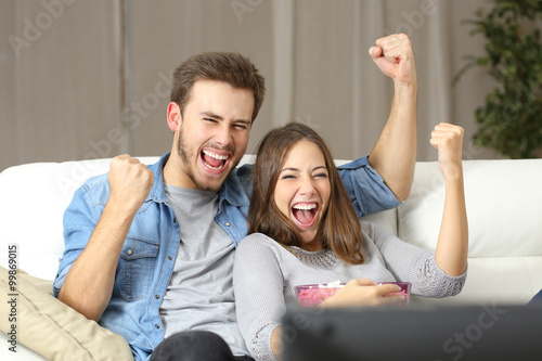 Obraz na plátně Euphoric couple watching tv at home