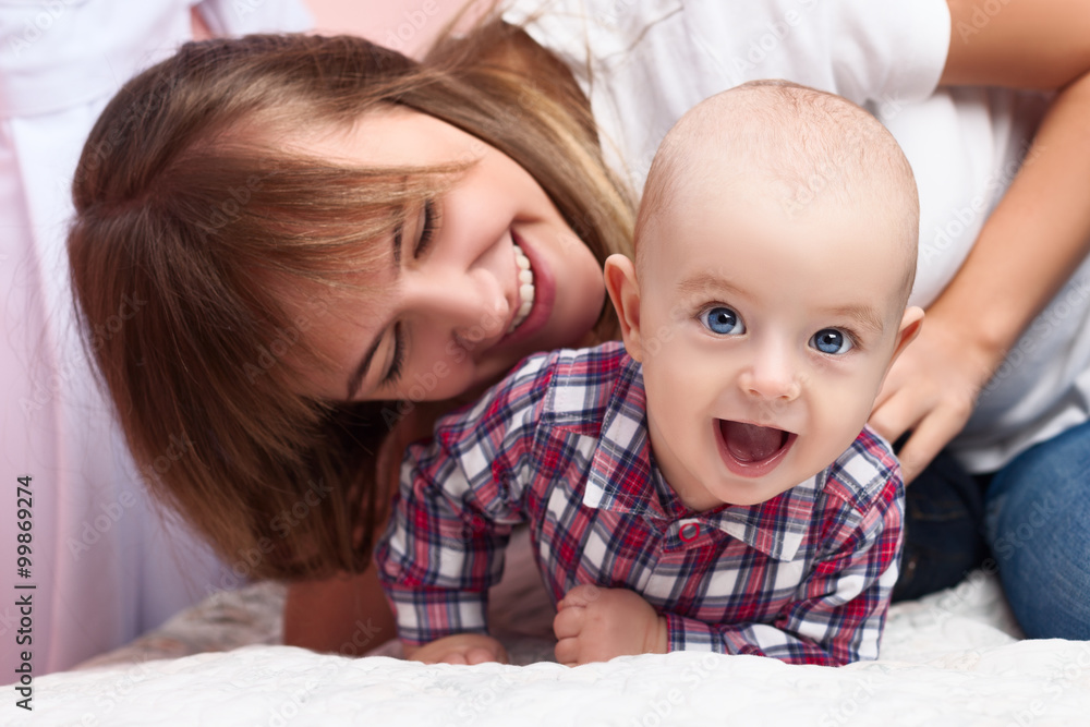 Portrait of smiling young beautiful woman playing with cute baby. Happy family concept Portrait of smiling young beautiful woman playing with cute baby. Happy family concept
