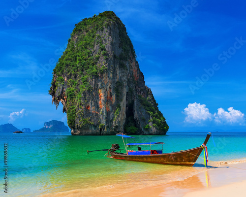 Wooden boat on exotic sandy beach with tropical sea at summer in Thailand
