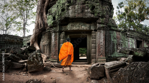 Buddhist monk enters Ta Prom Khmer ancient temple of Angkor Wat site in Cambodia