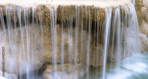 Cool fresh water falls from wet stone edge. Natural spring river stream close up background