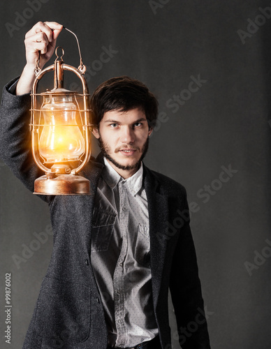Young man holding an oil lamp in the darkness.