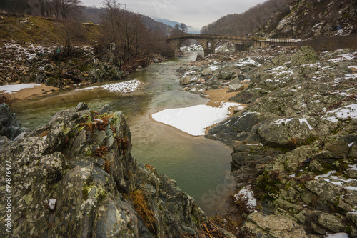 Bridge across river with green waters, snow and ice near Xanthi photo