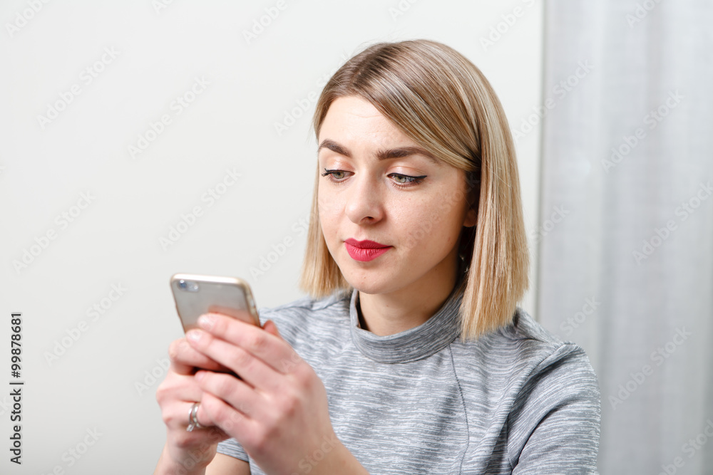 Young pretty business woman with mobile phone sitting at her workplace in office Young pretty business woman with mobile phone sitting at her workplace in office