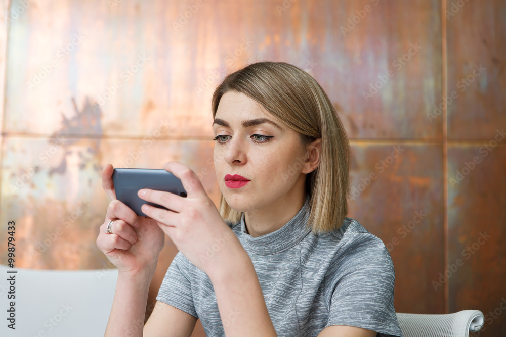 Young pretty business woman with mobile phone sitting at her workplace in office Young pretty business woman with mobile phone sitting at her workplace in office