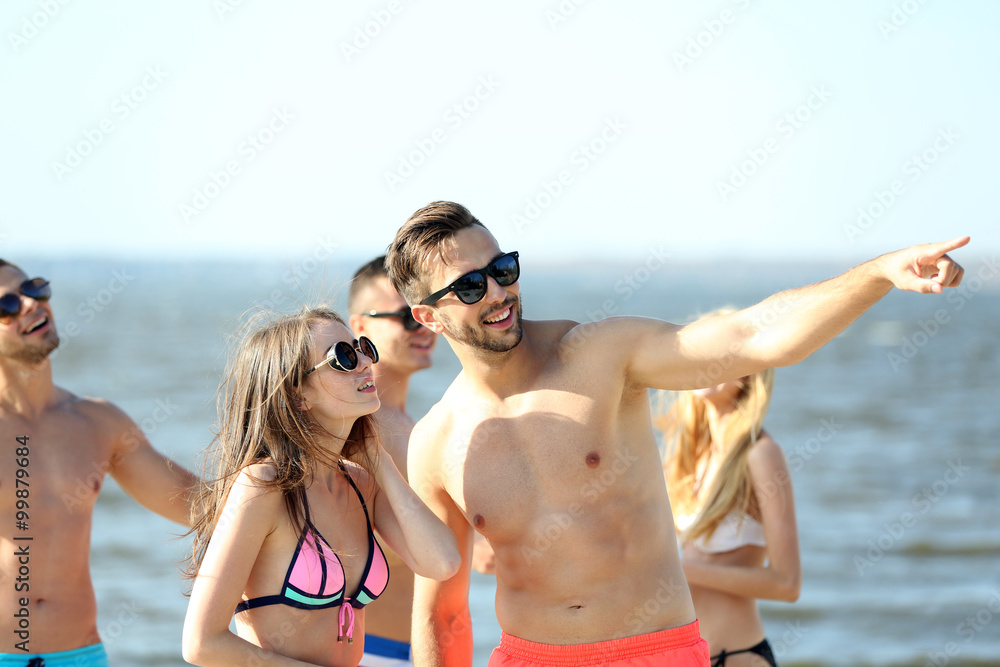 Happy couple and their playful friends relaxing at the beach, outdoors Happy couple and their playful friends relaxing at the beach, outdoors