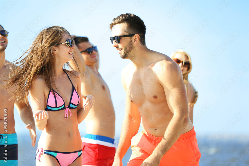 Happy couple and their playful friends relaxing at the beach, outdoors