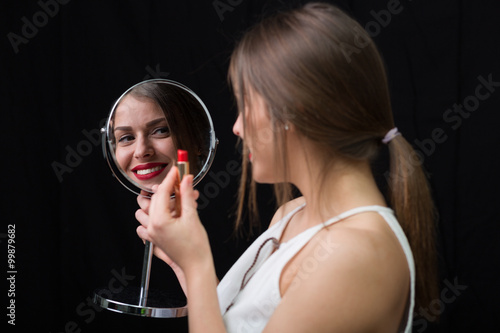 Woman with a mirror and a red lipstick
