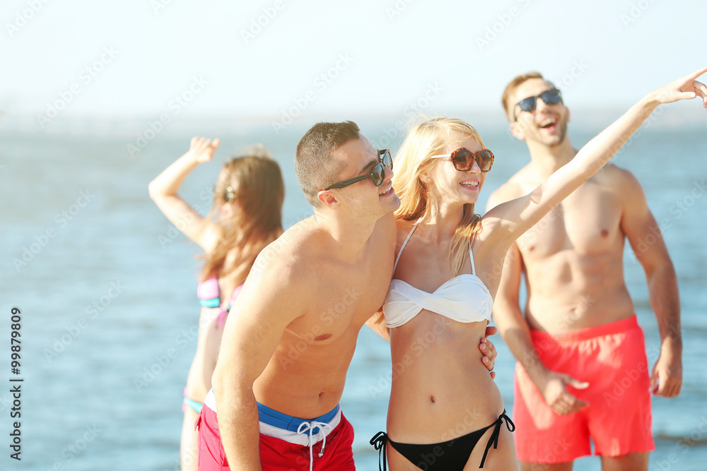 Happy couple and their playful friends relaxing at the beach, outdoors Happy couple and their playful friends relaxing at the beach, outdoors
