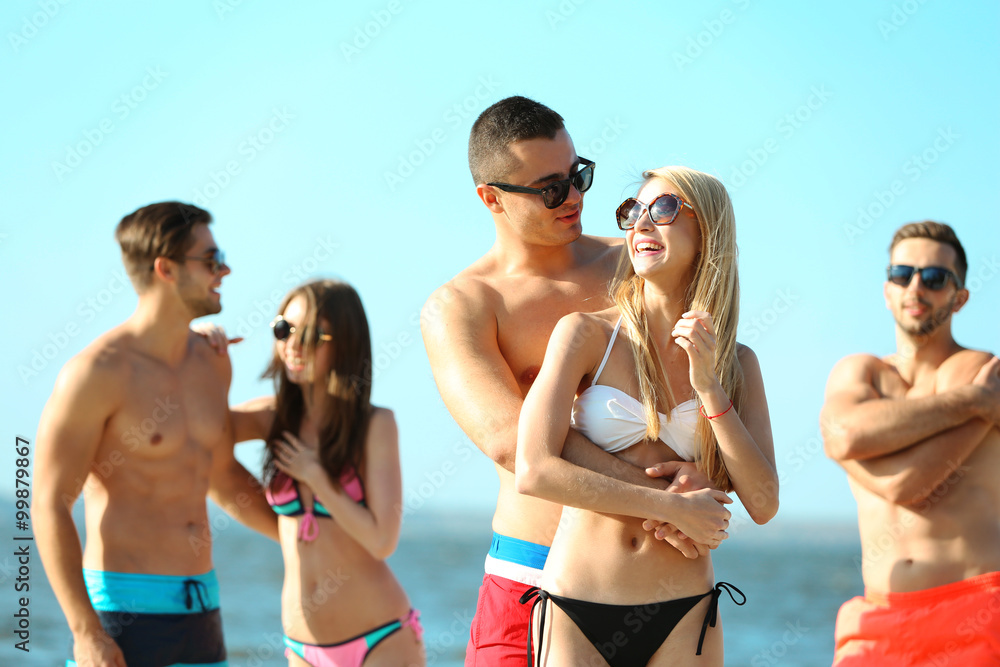 Happy couple and their playful friends relaxing at the beach, outdoors Happy couple and their playful friends relaxing at the beach, outdoors
