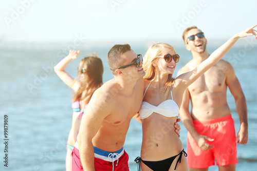 Happy couple and their playful friends relaxing at the beach  outdoors