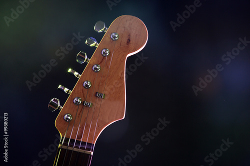 Part of electric guitar, on dark lighted background