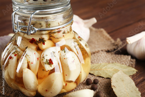 Canned garlic with spices on wooden background