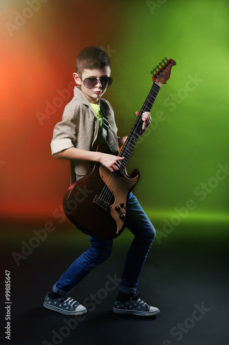 Little boy playing guitar on a bright background © Africa Studio