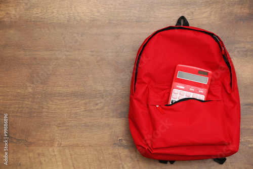 Backpack and calculator on wooden background photo