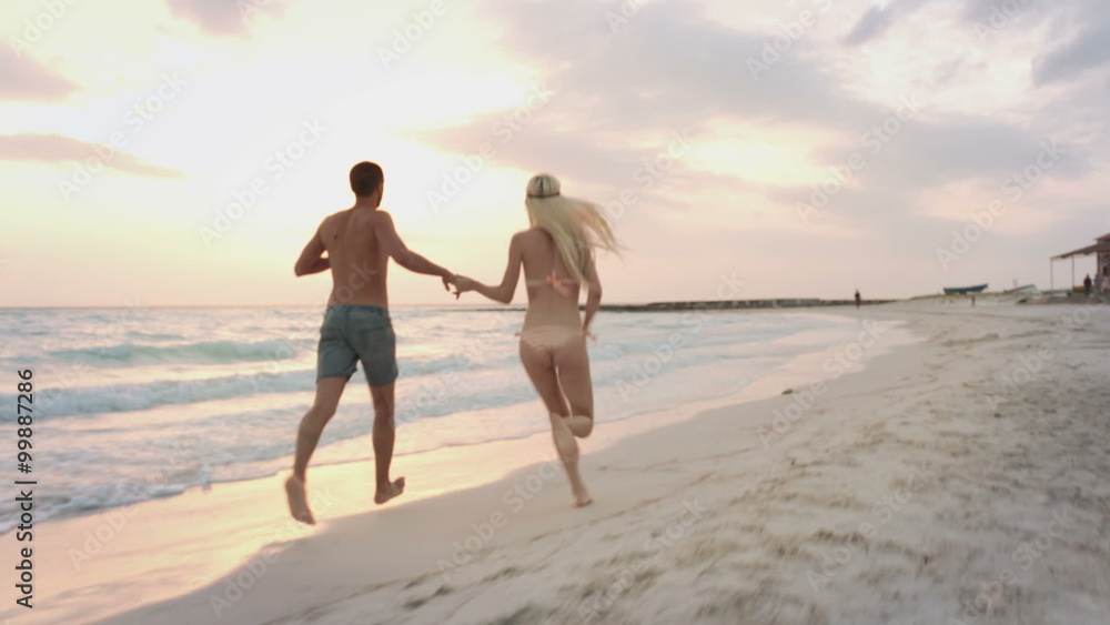 Back view couple run along sea side gimbal steadicam Back view couple run along sea side gimbal steadicam
