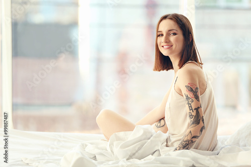 Attractive woman with tattoo sitting on the bed Free Download Attractive woman with tattoo sitting on the bed - GFXLoad