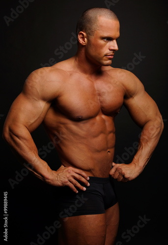 Muscular man poses on gray background