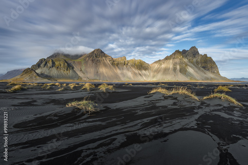 Black sand beach with mountain range background in sunny day Vesturhorn Iceland