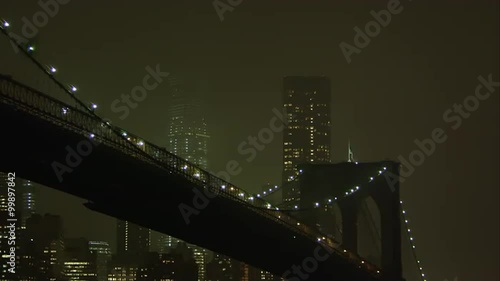 Static zoomed view at night overlooking the East River and the Brooklyn Bridge.