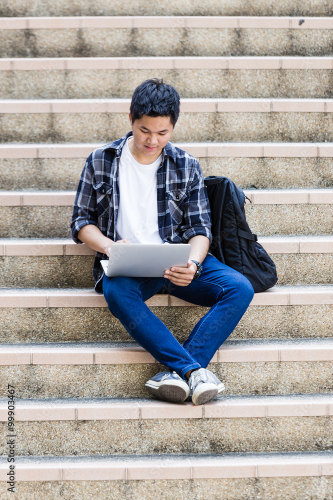 Young man sitting on the stairs using laptop