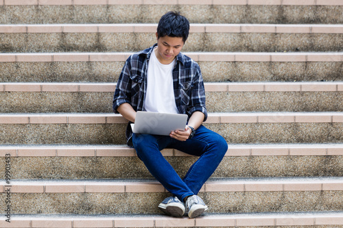 Young man sitting on the stairs using laptop