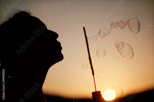 Happy blowing bubbles in the park at sunset. instagram tone, ret