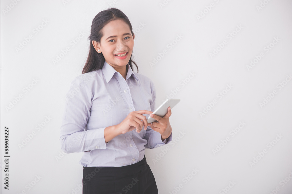 Asian Young secretary smiling while holding a cellphone. White b Asian Young secretary smiling while holding a cellphone. White b