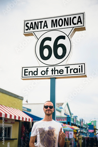 Happy Tourist in Historic Route 66 sign at Santa Monica Californ