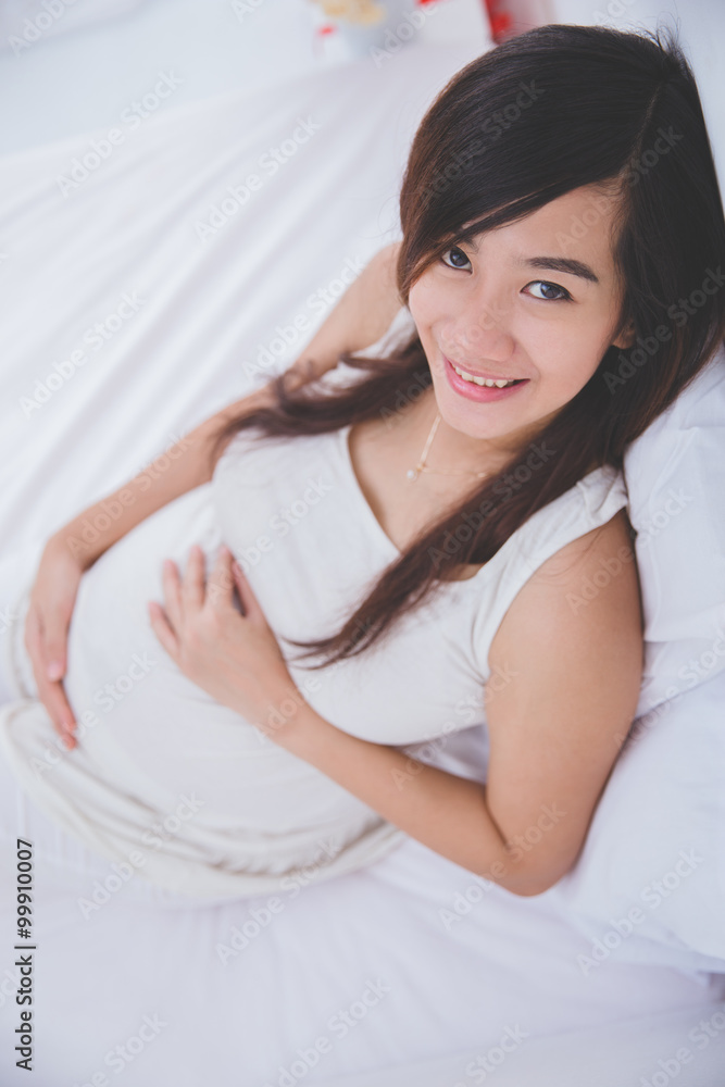 Beautiful pregnant woman smiling in to camera while lying on the Beautiful pregnant woman smiling in to camera while lying on the