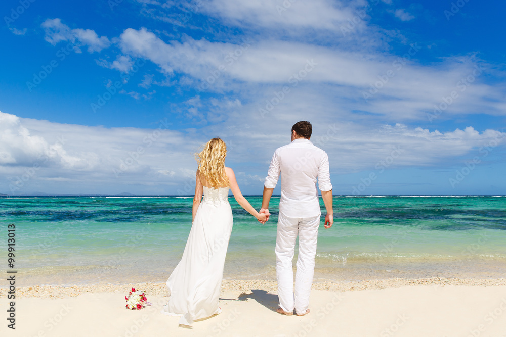 Bride and Groom having fun on the tropical beach with his back t