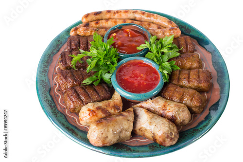 Plate of grilled sausages with red sauces.