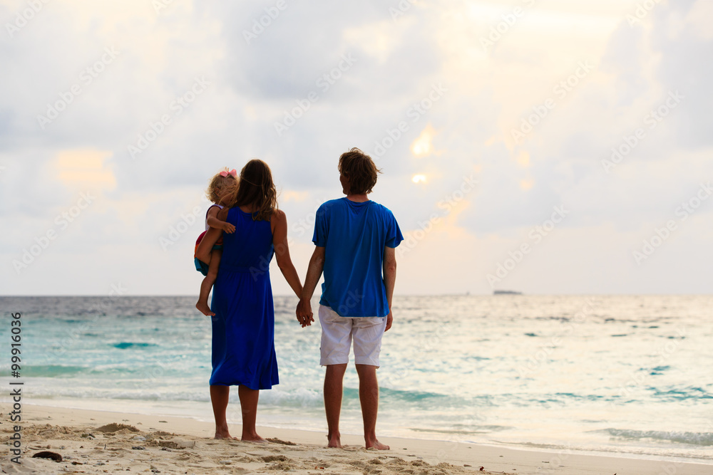 romantic couple with little child at sunset beach