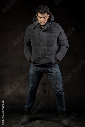 Full length portrait of a man wearing the winter jacket, dark background