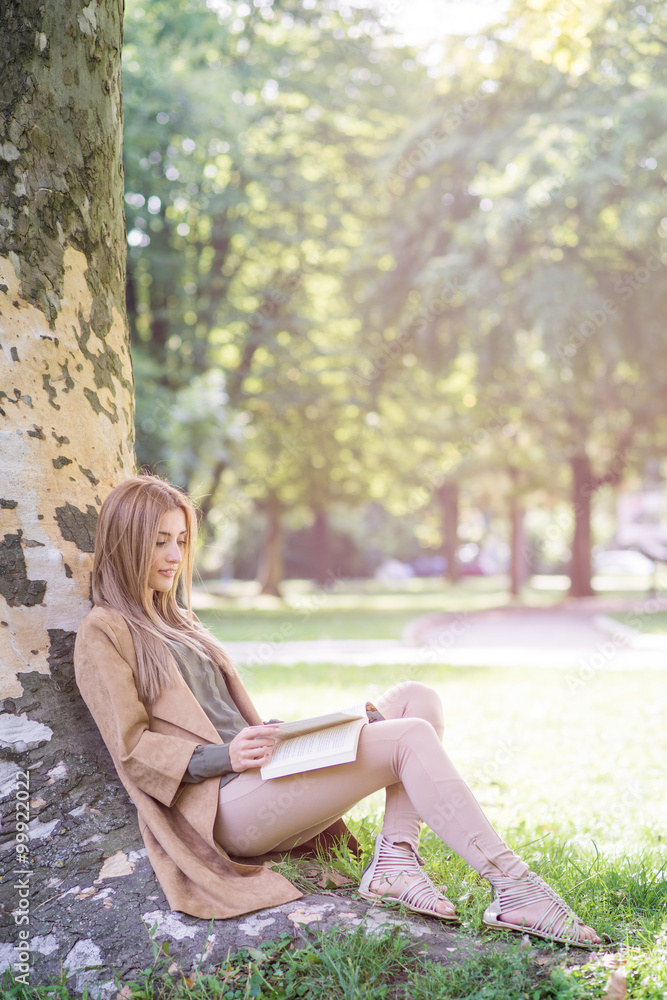 Young woman reading a book under a tree outdoor Young woman reading a book under a tree outdoor