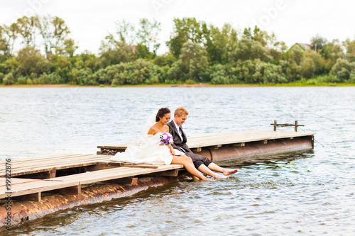 Beautiful bride with groom by a lake. Kiss and hug each other