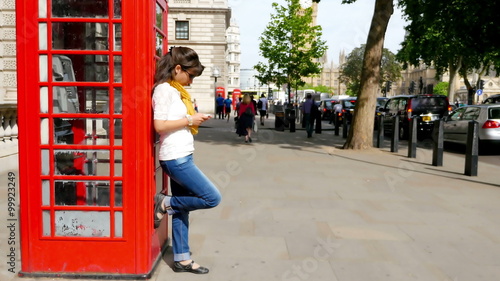Wallpaper Mural Woman using smart phone while leaning on a red phone booth Torontodigital.ca