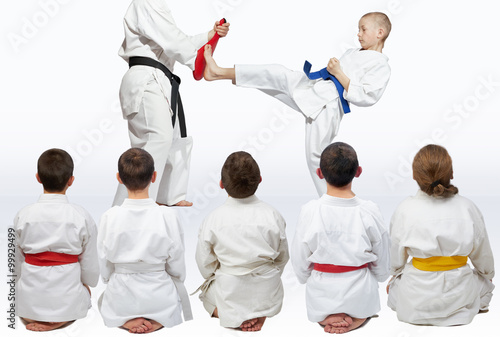 Sportsmen sitting in pose looking at demonstration punch karate
